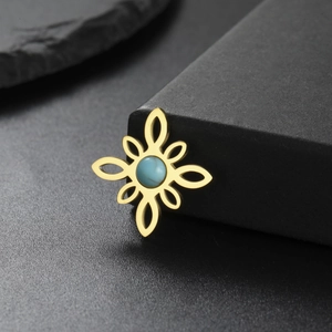 Detalle del colgante de flor dorada con calado artesanal e incrustación de gema azul