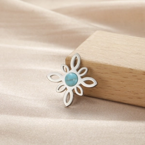 Detalle de un colgante de flor plateada con piedra azul sobre seda suave