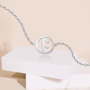 Detail of silver stainless steel chain bracelet with a circular rune letter F pendant
