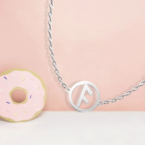 Close-up of a silver stainless steel necklace with a hollow letter F round pendant