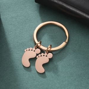 Close-up of rose gold footprint pendants on a polished stainless steel keychain ring