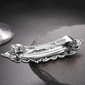 Macro detail of the spring clip structure and wavy metal carving on silver hair clip