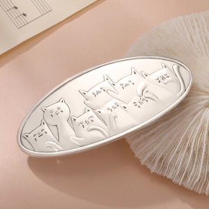 Vintage silver metal cat hair clip with embossed feline pattern on music sheet