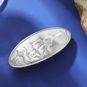Detail of silver alloy cat hair clip with matte brushed finish and embossed cat patterns