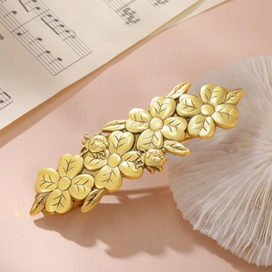 Close-up of golden vintage floral hair clip with ladybug details on retro sheet music