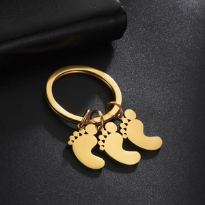 Polished gold baby footprints keychain with three charms on a minimalist ring