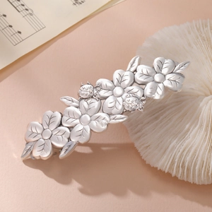 Macro detail of vintage silver flower hair clip with ladybug design on coral stand