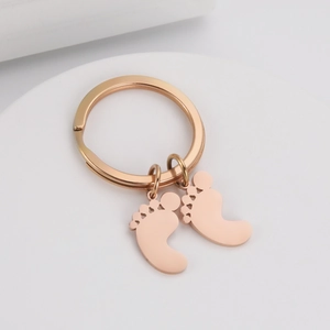 Macro view of baby footprint pendants in rose gold finish on a minimal metal keychain