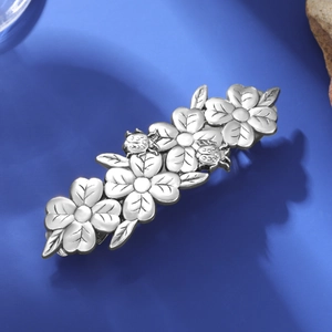 Detailed macro view of vintage silver floral hair clip with ladybug embossed texture