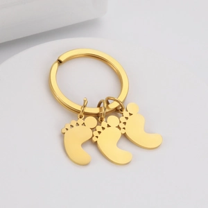 Close-up of golden stainless steel keychain featuring three baby footprint pendants