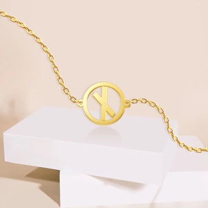 Detail view of 18K gold Viking rune pendant necklace on minimalist white geometric stands