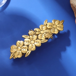 Macro detail of vintage gold floral hair clip with ladybug design on blue display