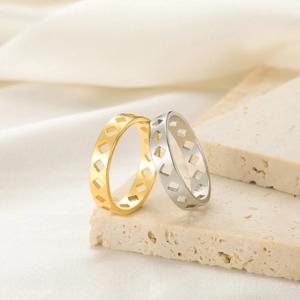 Anillos geométricos calados en acabados oro y plata sobre una base de piedra