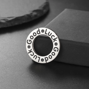 Polished stainless steel Good Luck ring pendant on minimalist dark stone background