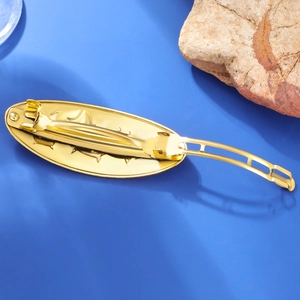 Detail of the golden metal hair clip spring mechanism on a textured blue surface