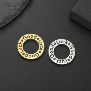 Detail of round Good Luck pendants in gold and silver steel on a dark textured surface