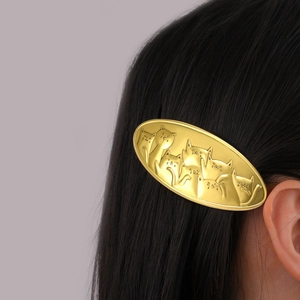 Golden alloy side hair clip with embossed cat designs on sleek black straight hair