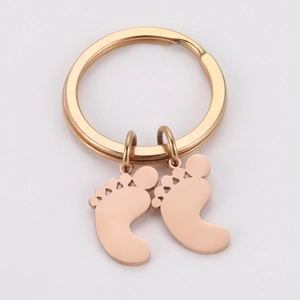 Macro detail of rose gold baby feet pendants on a polished metal keychain ring