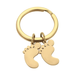 Detail of polished gold stainless steel baby feet pendants on a flat key ring