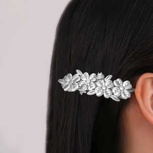 Elegant silver flower hair clip with metallic leaves on black hair side view