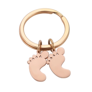 Macro view of rose gold baby feet pendants on a polished stainless steel keychain