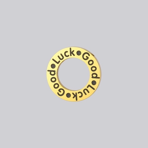 Close-up of golden Good Luck pendant with black engraved lettering and polished finish