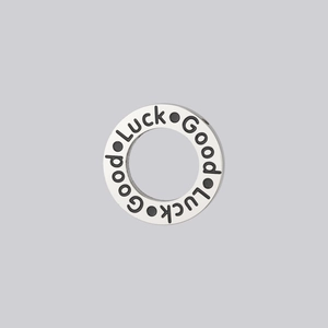 Detail of silver stainless steel charm with engraved black Good Luck lettering
