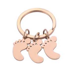 Detailed close-up of rose gold baby feet pendants with heart cutouts on a metal keychain