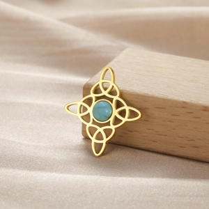 Detalle del colgante nudo celta dorado con piedra azul sobre seda color champán