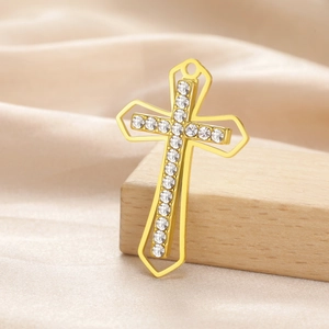 Detail of a gold double-layer cross pendant with sparkling crystals on silk background