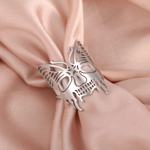 Anello teschio farfalla in acciaio inossidabile esposto su elegante tessuto di raso rosa
