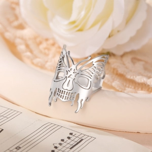 Dettaglio macro dell'anello a farfalla con teschio d'argento su spartiti e rose
