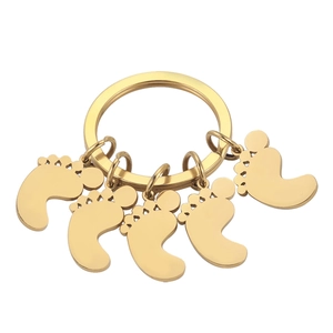 Detailed view of five golden stainless steel baby footprint charms on a metal keychain