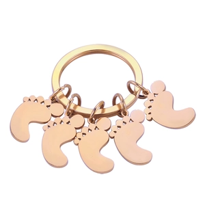 Detail shot of five polished rose gold baby footprint charms on a stainless steel keyring