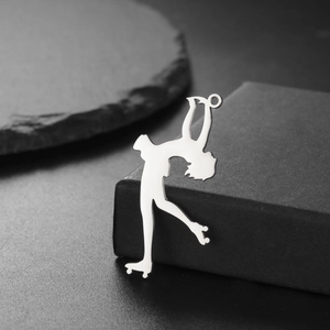 Polished silver roller skating figure pendant resting on a textured dark background