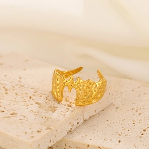 Macro detail of gothic 18K gold plated bat wing ring with irregular lava textures
