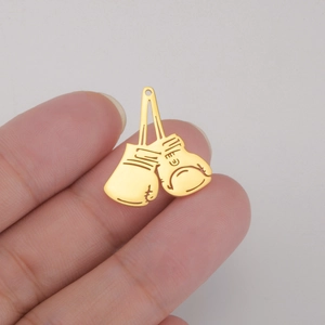 Gros plan d'une paire de pendentifs gants de boxe dorés tenus entre les doigts pour la taille