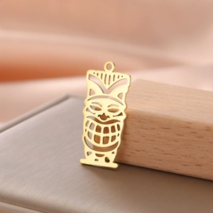 Detailed view of hollow 18K gold plated Tiki mask pendant on elegant silk and leather background