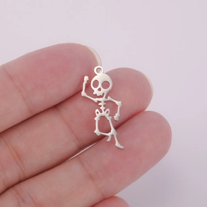 Macro shot of a polished silver stainless steel skeleton pendant held between fingers