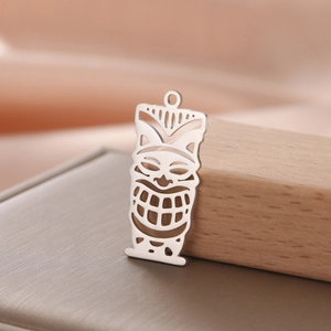 Macro view of a hollowed-out stainless steel Tiki mask pendant with a metallic luster finish