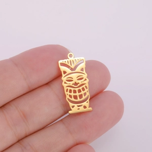 Macro shot of gold-plated hollow Tiki mask pendant held in hand for scale detail