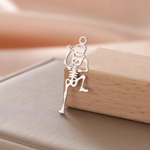 Macro view of a silver skeletal skull pendant with top hat on light wood surface