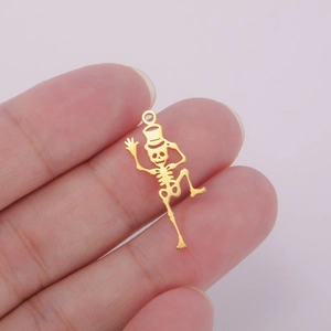 Macro detail of a 18K gold plated hollow dancing skeleton charm held by fingers