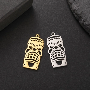 Detailed macro view of 18K gold and silver plated hollow Tiki mask charms in tribal style