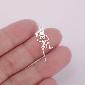 Macro shot of 18K gold plated hollow dancing skeleton charm on a fingertip for size reference