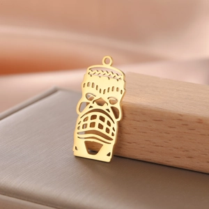 Detailed macro of 18K gold plated hollow Tiki mask pendant on a wooden prop