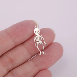 Detailed macro shot of a hollow skeleton pendant held between fingers for size reference