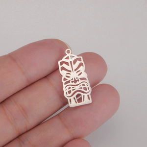 Detail showing hand holding a polished silver hollow Tiki mask pendant for DIY jewelry making