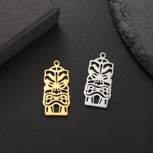 Detail of 18K gold and silver plated tiki mask pendants with intricate hollowed designs