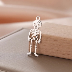 Macro shot of a hollow skull pendant in silver steel on a wooden block for DIY jewelry making